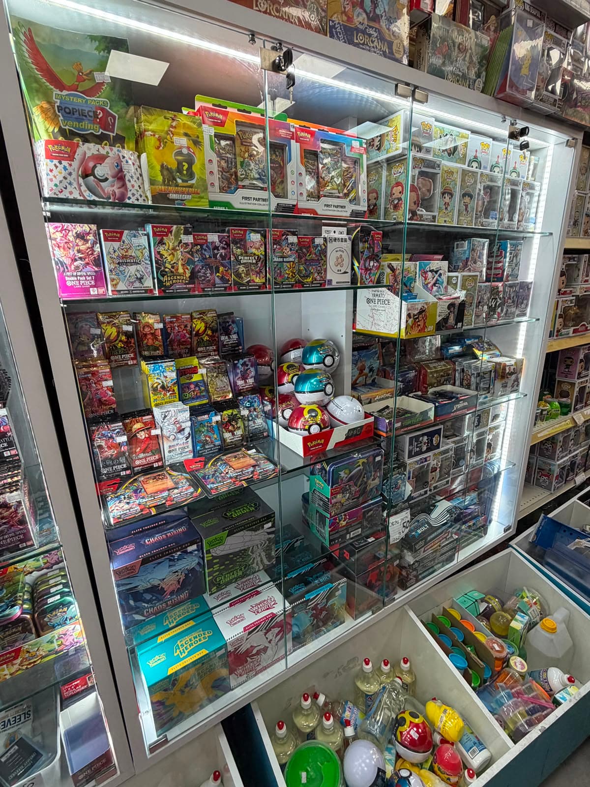 ויטרינת קלפי פוקימון, One Piece, Disney Lorcana, פיגרים ומוצרי TCG בחנות מיסטר הליום באשקלון.