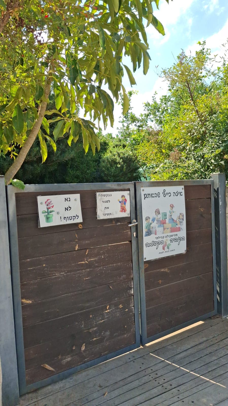 שער כניסה עץ ומתכת למוזיאון הלגו הקהילתי "הקוביה הקסומה" עם שלטי הכוונה מאוירים.