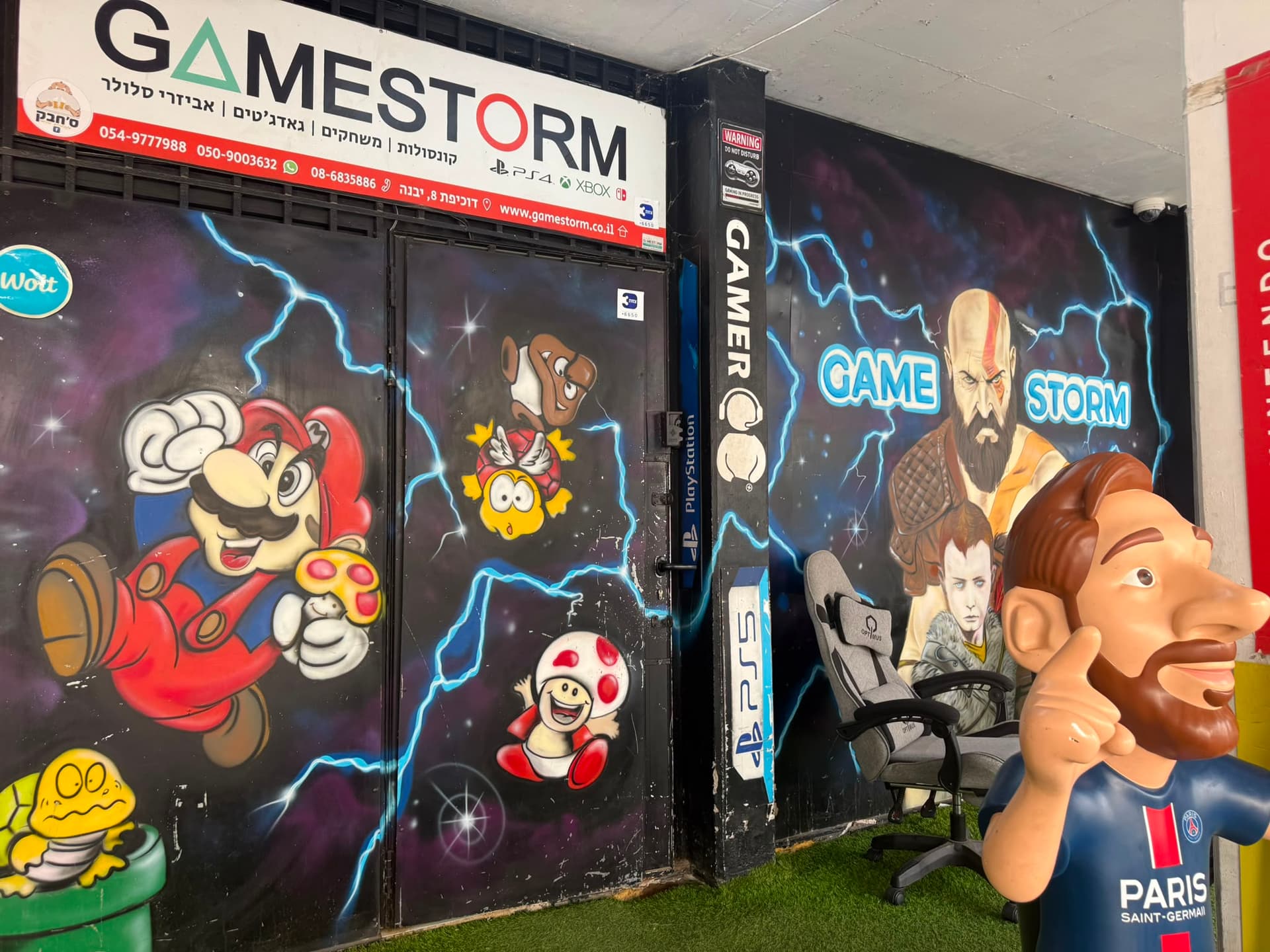 חנות הגיימינג GameStorm ביבנה, מעוטרת בגרפיטי צבעוני ופסל של מסי בחוץ.